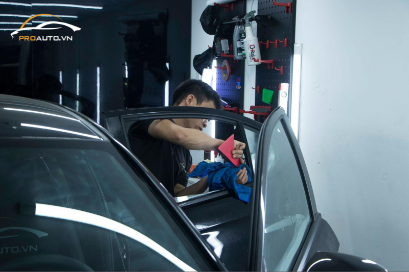 Kỹ thuật viên vệ sinh phần kính xe trước khi dán phim