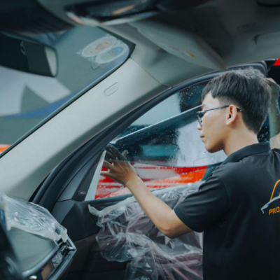 Kỹ thuật viên thi công dán phim cách nhiệt cho kính tài phụ của xe
